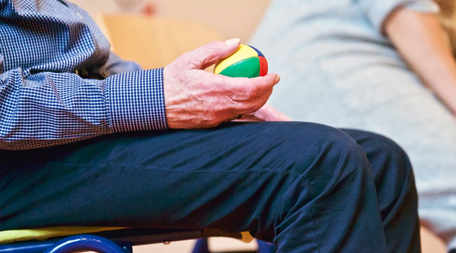 Ältere Hand hält einen farbigen Igelball zur Handtherapie